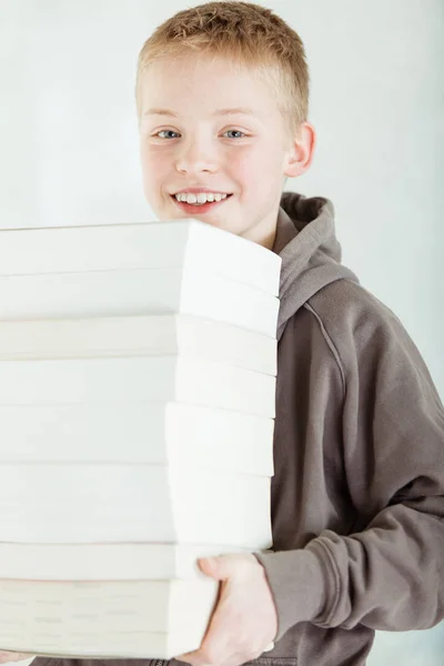 Garçon portant une pile de livres — Photo