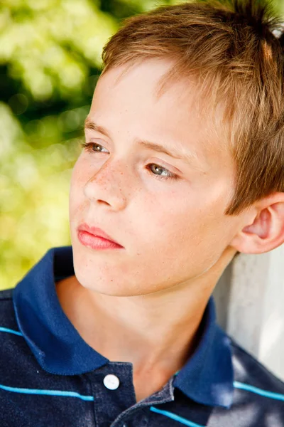 Portrét mladého chlapce, který seděl v zahradě — Stock fotografie