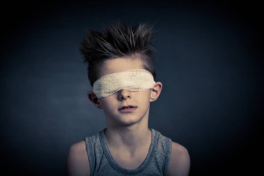 Young Boy with Bandage on Eyes Against Gray clipart