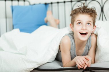 Onun yatakta battaniye ile mutlu düşünceli çocuk yalan