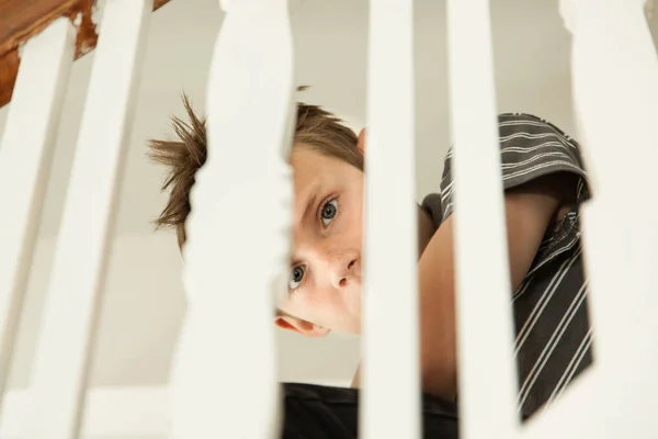Jongen op zoek bang zijn door de leuning van een trap — Stockfoto