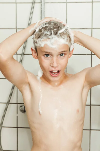 Boy washing his hair in the shower — Stockfoto