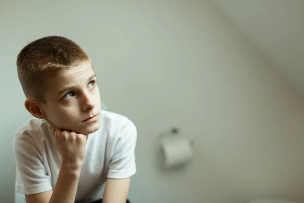 Thoughtful Schoolboy Sits on Toilet and Looking Up — Stock Photo, Image