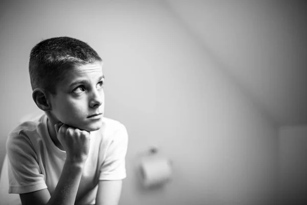 Ragazzo contemplativo seduto sul water in monocromatico — Foto Stock