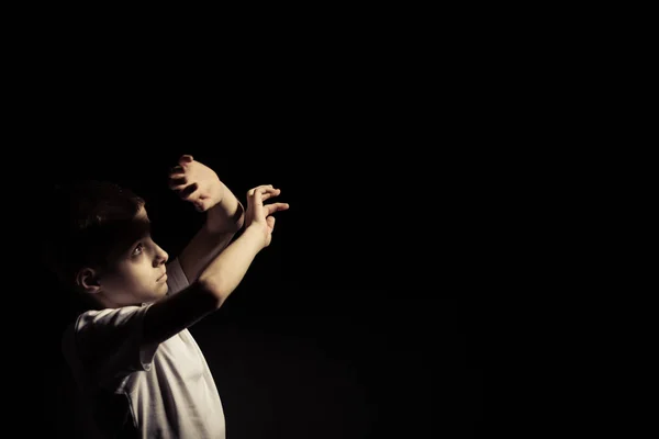 Jongen op zoek Up terwijl die betrekking hebben op licht tegen zwart — Stockfoto