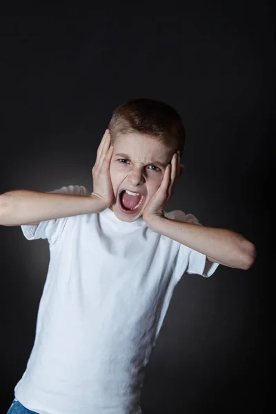 Podrážděný Boy výkřiky na kameru s rukama na obličej — Stock fotografie