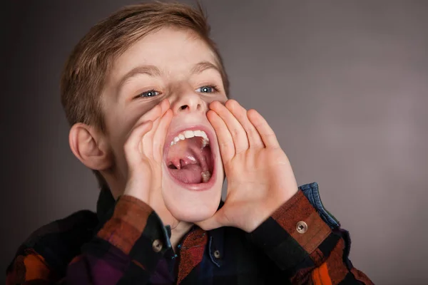 Jonge jongen schreeuwen in de verte tegen grijs — Stockfoto