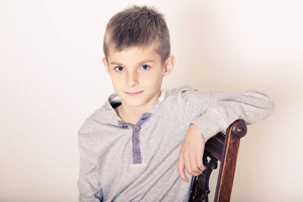 Leuke jongen scheve Arm op de rug van een stoel zitten — Stockfoto