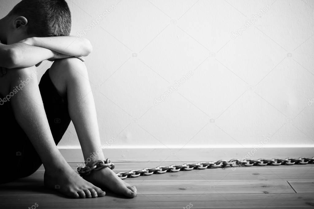 Sad Boy Sitting with Chain on Foot in Monochrome