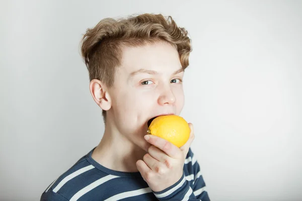 Маленький мальчик собирается укусить свежий лимон — стоковое фото