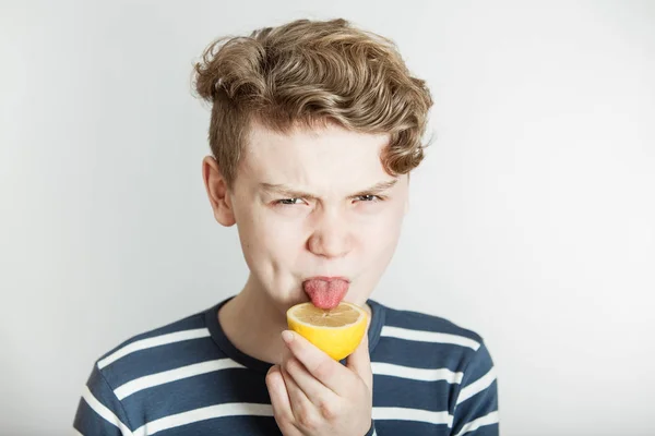 Мальчик облизывает кислый лимон языком — стоковое фото