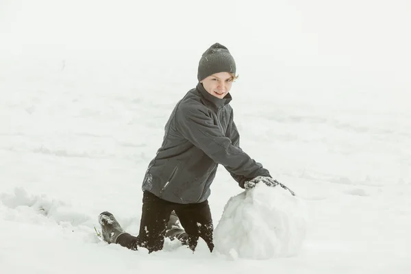 Chłopiec, tworząc duży snowball poza — Zdjęcie stockowe