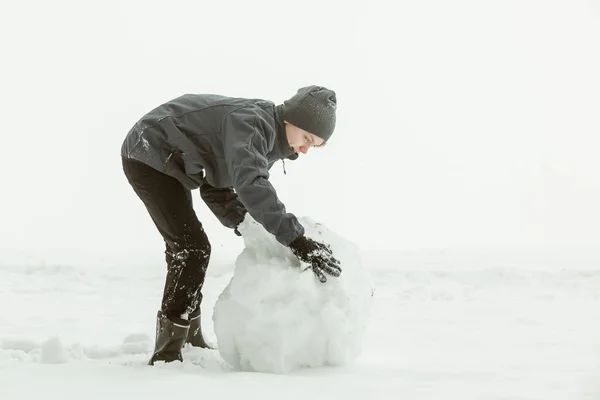 Widok z boku chłopca toczenia duży snowball — Zdjęcie stockowe