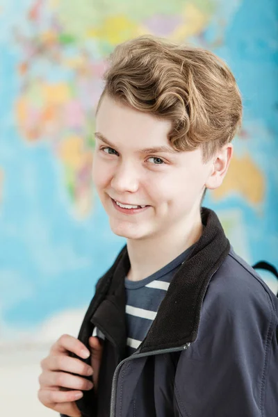 Sorrindo menino de pé na sala de aula segurando mochila — Fotografia de Stock