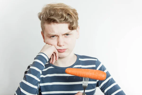 Надутый мальчик с вилкой, застрявший в моркови — стоковое фото