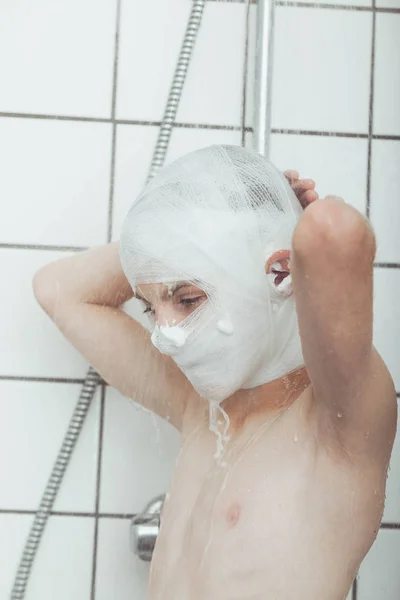 少年は、包帯を頭にシャワーを浴びて — ストック写真