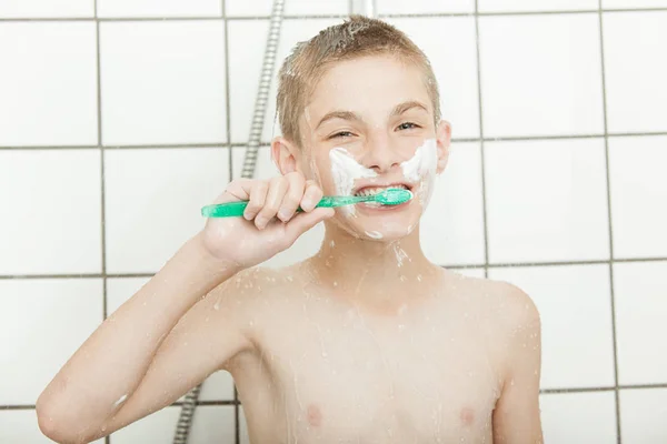 Boy brushing his teeth in shower — Stockfoto