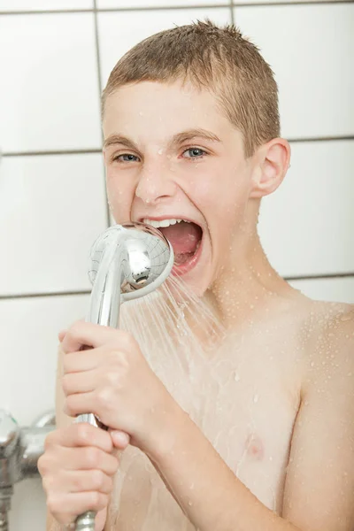 Muchacho mordiendo auriculares de ducha —  Fotos de Stock