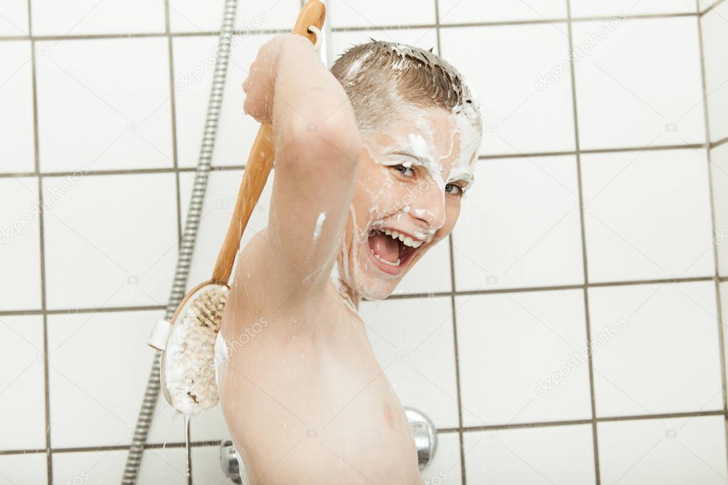Young boy showering using back brush