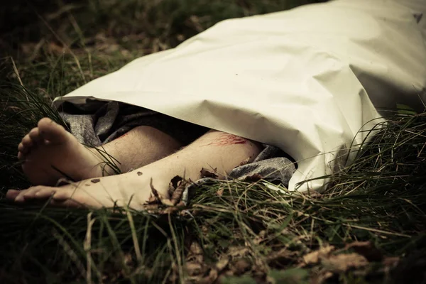 Жертва убийства лежит на улице под простыней — стоковое фото