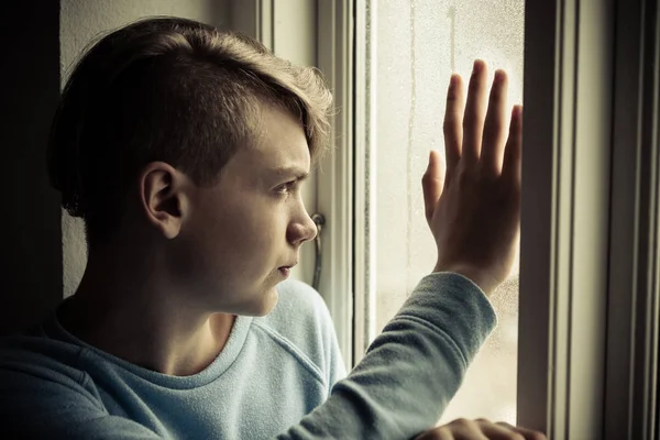 Adolescente triste olhando para fora da janela — Fotografia de Stock