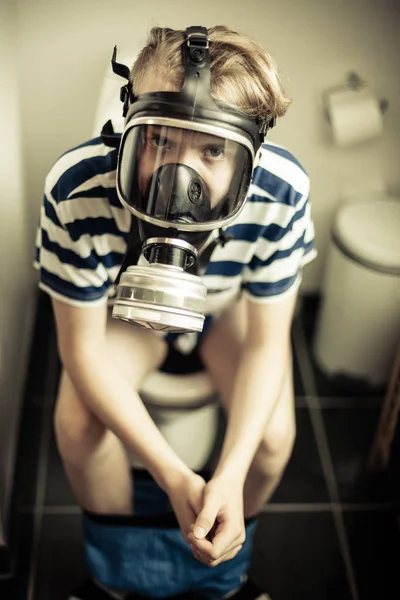 Young boy on toilet wearing gas mask — Stock Photo, Image