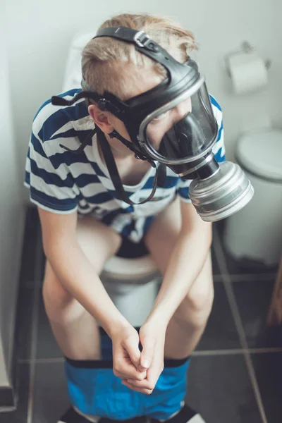 Giovane ragazzo sulla toilette indossando maschera antigas — Foto Stock