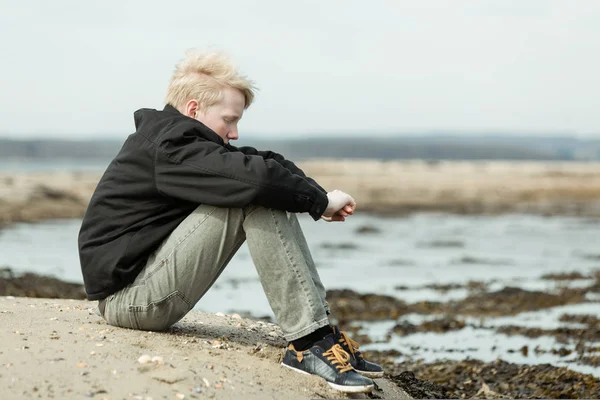 Eenzaam kind met armen rond de knieën buiten — Stockfoto