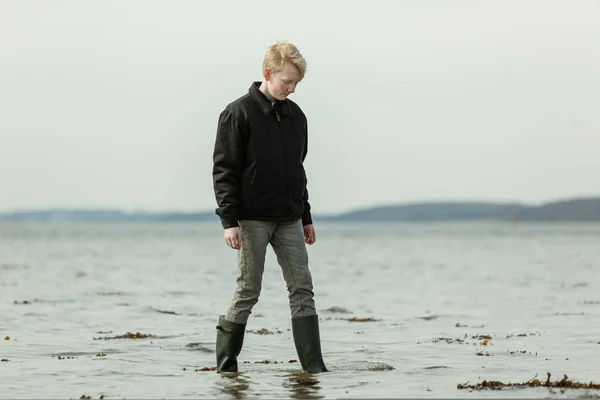 Jeune adolescent marchant dans l'eau pendant la marée haute — Photo