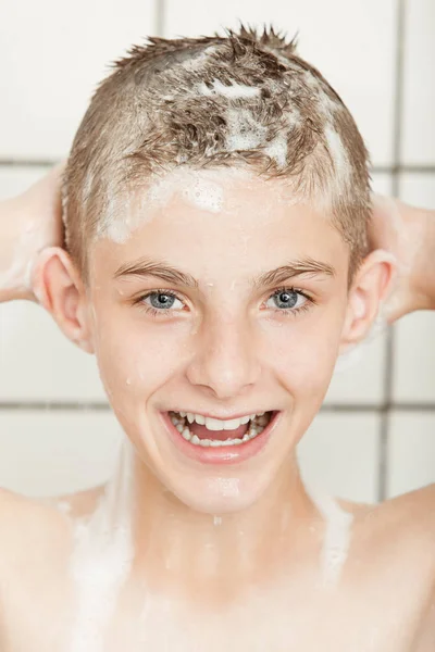 Fun charismatic young boy in a shower — Stockfoto