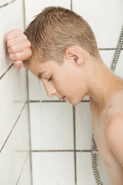 Mladý chlapec opřený o dlaždice sprcha — Stock fotografie