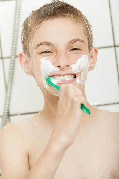 Happy little boy cleaning his teeth in the shower — Stockfoto