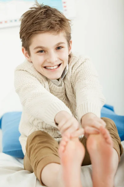 Boldog mosolygó fiatal fiú nyúlik a lábujjai — Stock Fotó