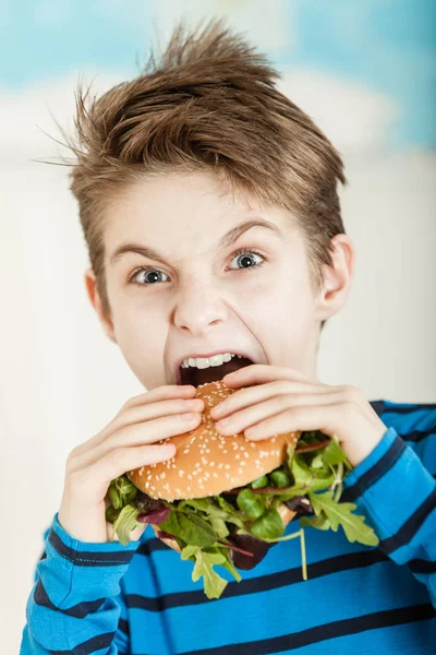 Junge beißt in Salat-Burger — Stockfoto