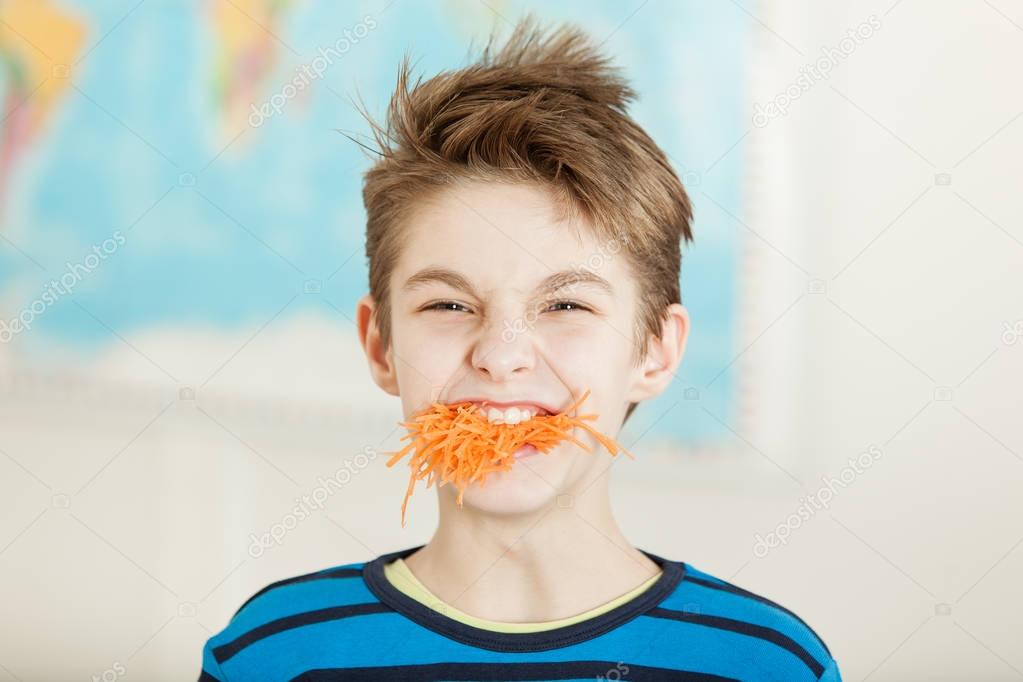 Young boy with a mouthful of grated carrot