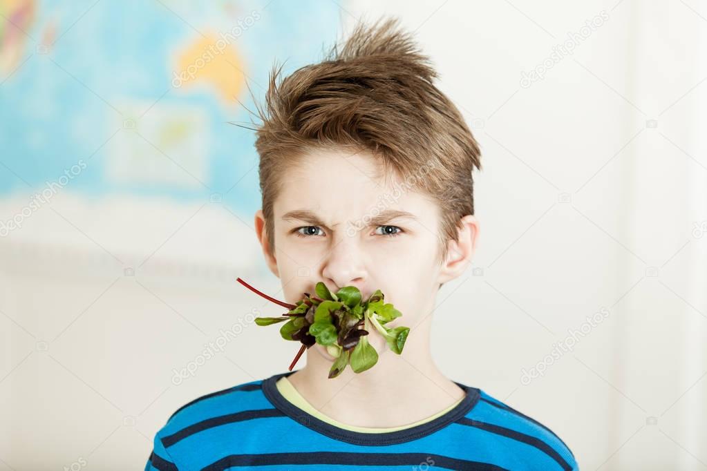 Young boy with his mouth stuffed with baby spinach