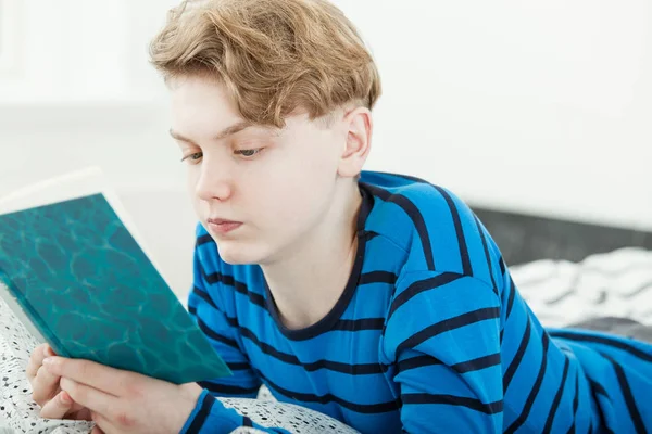 Handsome young teenage boy relaxing with a book — Stock Photo, Image