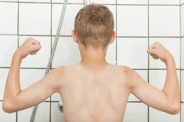 Achteraanzicht van kind buigen biceps in douchebox — Stockfoto