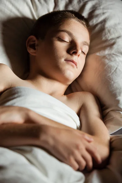 Cerca de niño con los brazos cruzados dormidos en la cama —  Fotos de Stock