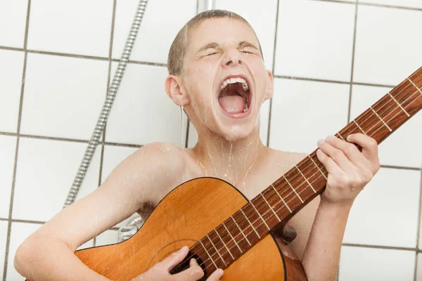 Alto niño cantando y tocando la guitarra en la ducha — Foto de Stock