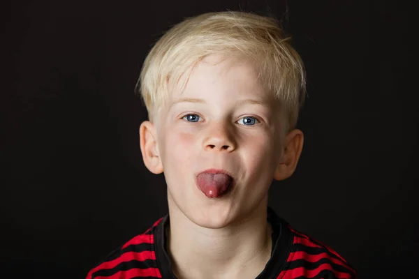 Hravý malý Plavovlasý chlapec trčí svůj jazyk — Stock fotografie