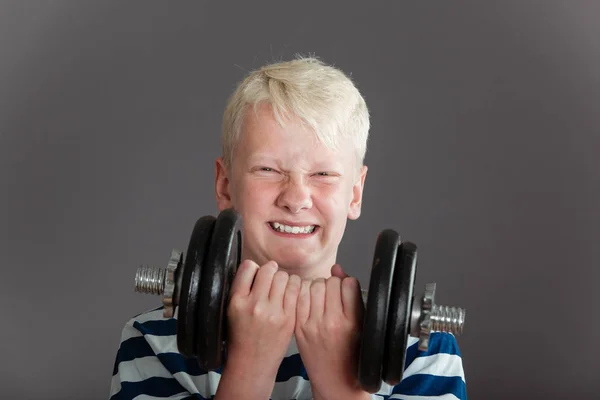 Blonde jongen probeert op te heffen van zware halter — Stockfoto