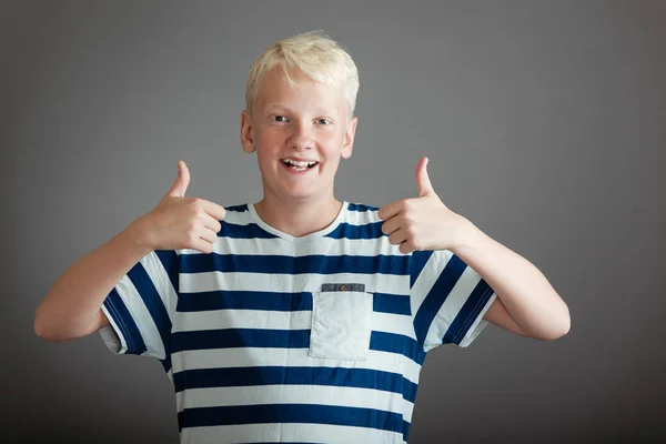 Glada blond tonåring i randig skjorta med tummen upp — Stockfoto