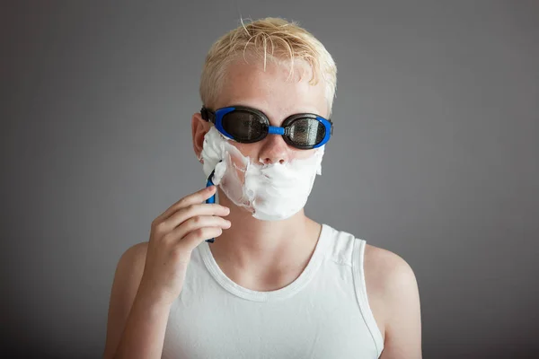 Boy using razor blade to remove shaving cream — Stock Photo, Image