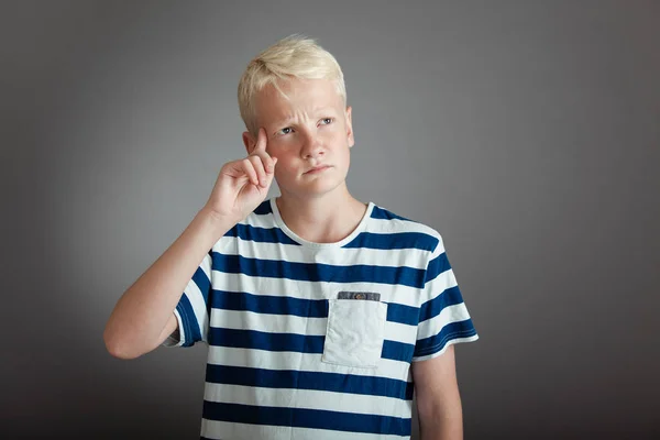 Blond boy thinking while pointing to his head Royalty Free Stock Photos