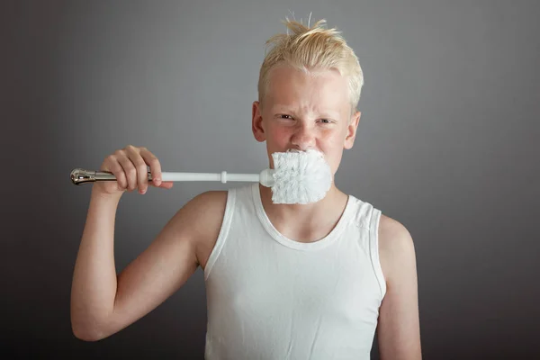 Boy scratching nose with toilet scrubber Royalty Free Stock Photos