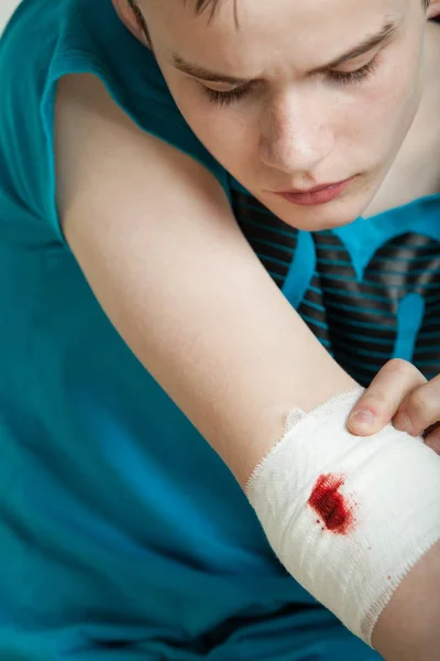 Dospívající chlapec při pohledu na zraněn a obvaz lokte — Stock fotografie
