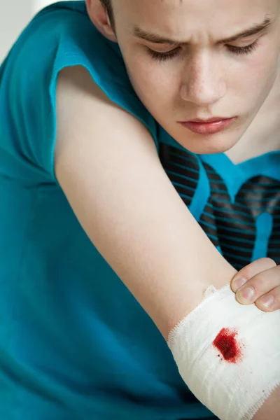 Male teenager concerned about his wounded elbow Stock Image