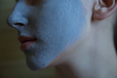 Young beautiful woman facial clay mask clipart
