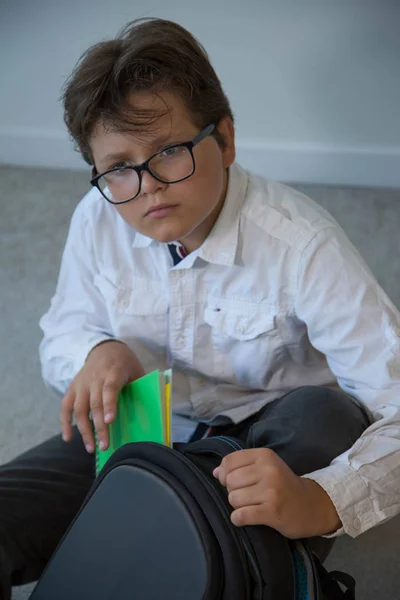 Allvarliga unga skola pojke sätta notebook i ryggsäck — Stockfoto